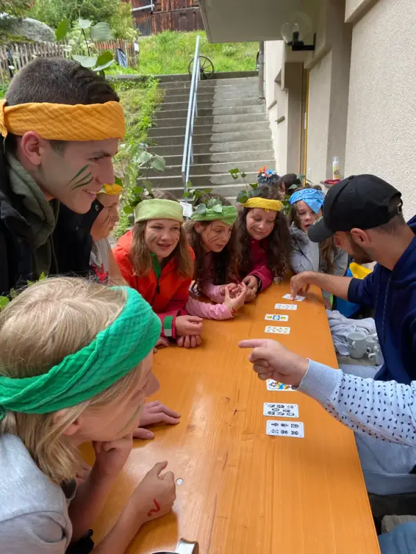Eine Gruppe von Kindern, die um einen Tisch herum sitzen und Karten spielen. – Jugend und Hund Lager 2020 in Segnas