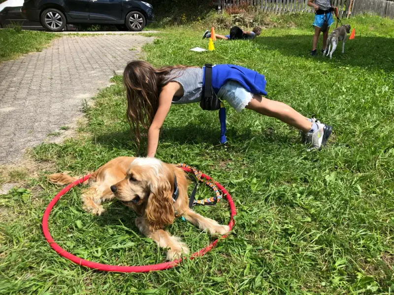 Eine Frau spielt mit einem Hund im Gras. – Jugend und Hund Lager 2020 in Segnas