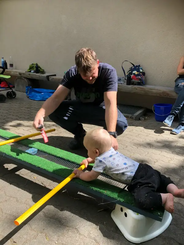Ein Mann und ein Baby spielen mit einem Spielzeug. – Jugend und Hund Lager 2020 in Segnas