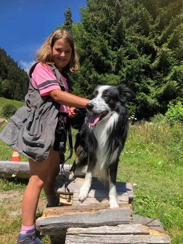 Ein Mädchen streichelt einen Hund auf einer hölzernen Plattform. – Jugend und Hund Lager 2020 in Segnas