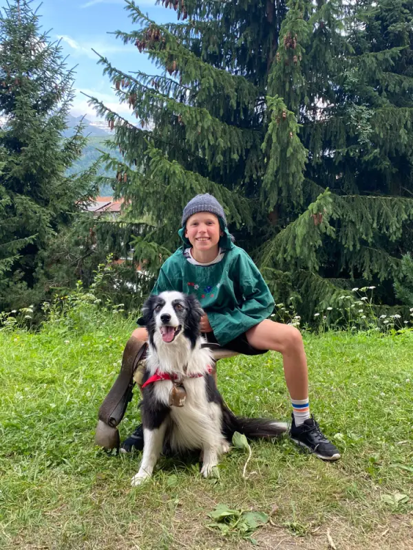 Ein Junge und sein Hund sitzen im Gras. – Jugend und Hund Lager 2021 in Segnas