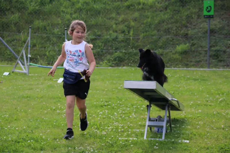 Ein kleines Mädchen läuft mit einem Hund in einem Feld. – Jugend und Hund Lager 2021 in Segnas