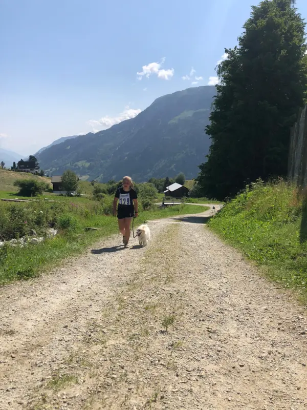 Eine Frau, die mit einem Hund eine unbefestigte Strasse hinuntergeht. – Jugend und Hund Lager 2021 in Segnas