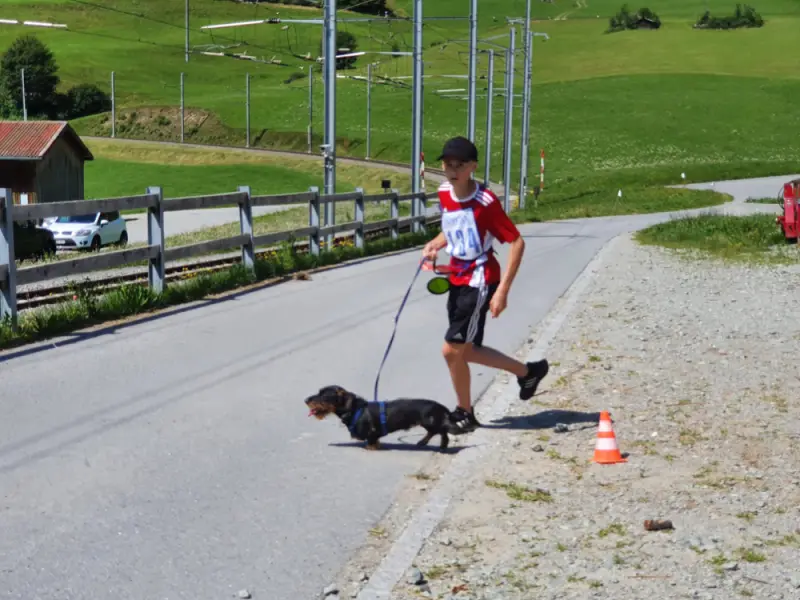 Ein Mann, der einen Hund auf einer Strasse läuft. – Jugend und Hund Lager 2021 in Segnas