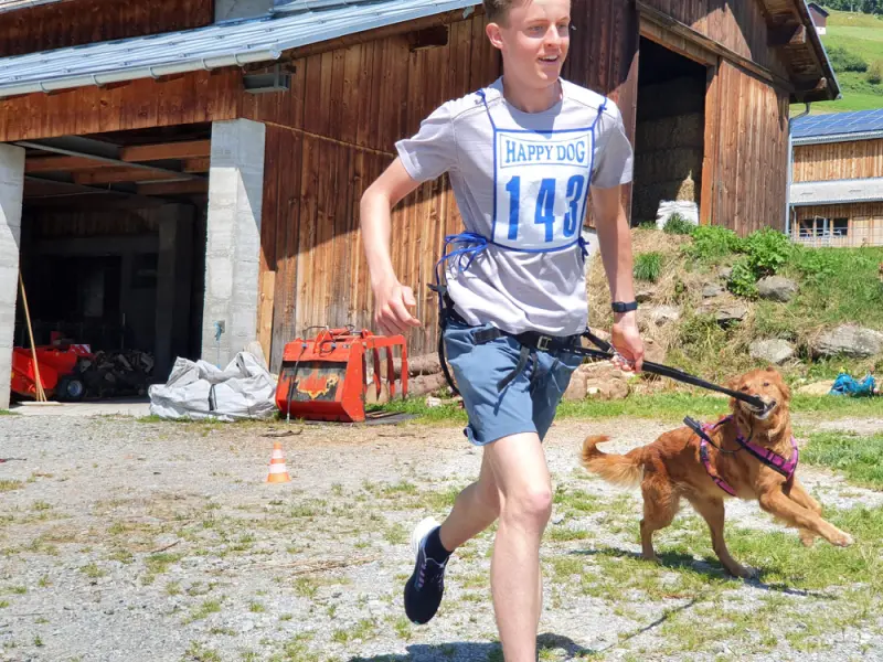 Ein junger Junge läuft mit einem Hund in einem Hof. – Jugend und Hund Lager 2021 in Segnas