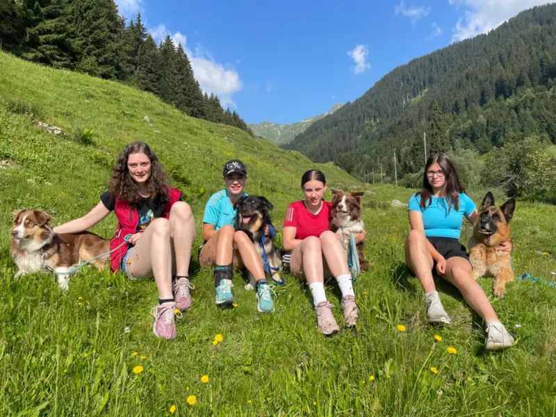 Vier Mädchen und ihre Hunde sitzen im Gras. – Jugend und Hund Lager 2021 in Segnas