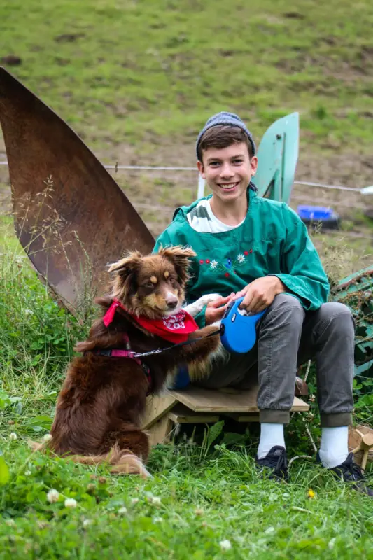Ein Junge sitzt auf einer Bank mit einem Hund. – Jugend und Hund Lager 2021 in Segnas
