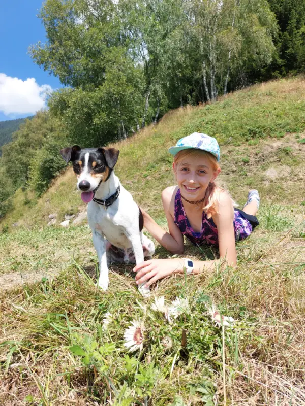 Ein junges Mädchen, das mit ihrem Hund auf dem Boden liegt. – Jugend und Hund Lager 2022 in Segnas