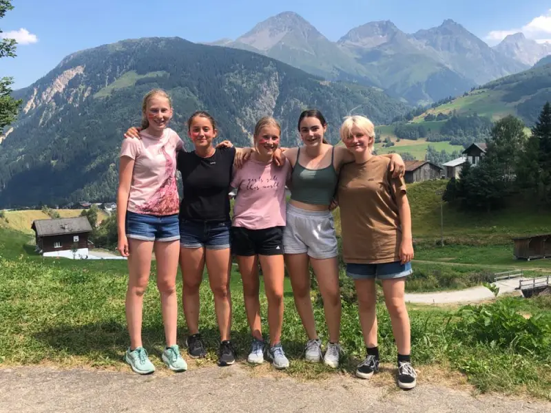 Drei Mädchen stehen vor einem Berg. – Jugend und Hund Lager 2022 in Segnas