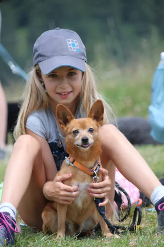 Ein kleiner Hund, der ein kleines Mädchen hält. – Jugend und Hund Lager 2022 in Segnas