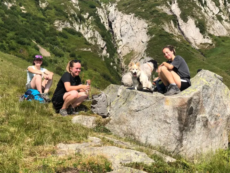Zwei Personen sitzen auf einem Felsen mit einem Hund. – Jugend und Hund Lager 2022 in Segnas