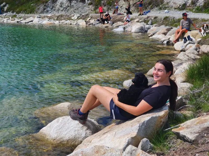 Eine Frau, die auf einem Felsen neben einem Gewässer sitzt. – Jugend und Hund Lager 2022 in Segnas