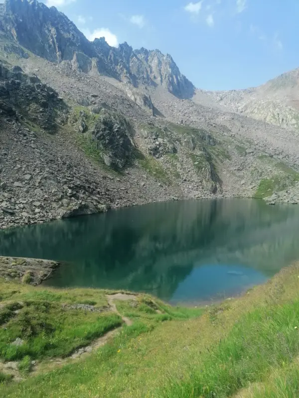 Ein See in den Bergen mit einer Bergkette im Hintergrund. – Jugend und Hund Lager 2022 in Segnas