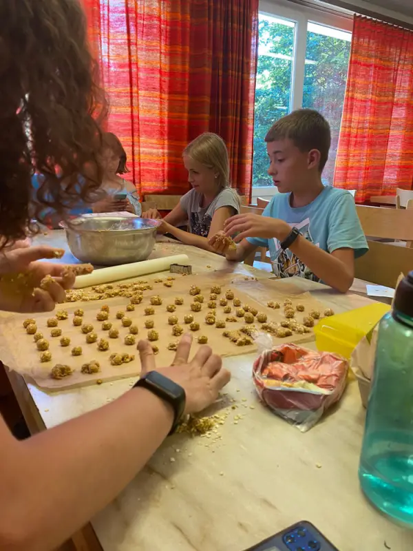 Eine Gruppe von Kindern, die um einen Tisch sitzen und Kekse machen. – Jugend und Hund Lager 2022 in Segnas