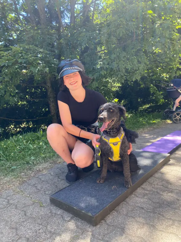 Eine Frau kniet mit einem Hund auf einer Bank nieder. – Jugend und Hund Lager 2022 in Segnas
