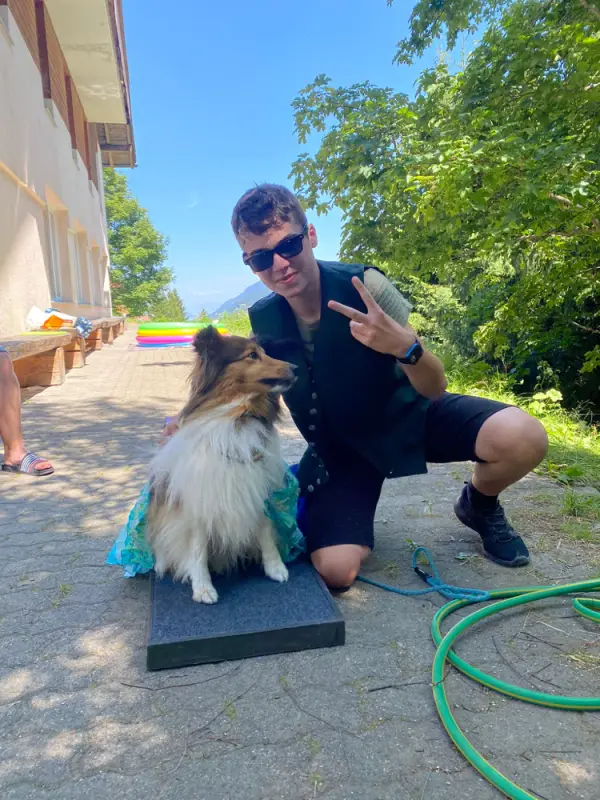 Ein Mann kniet mit einem Hund an der Leine nieder. – Jugend und Hund Lager 2022 in Segnas