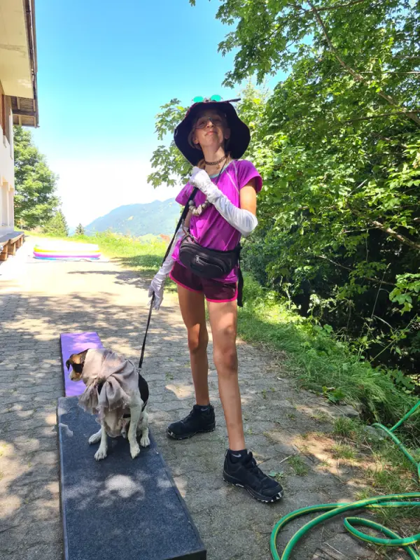 Eine Frau in einem lila Hemd und schwarzer Hut geht einen Hund. – Jugend und Hund Lager 2022 in Segnas