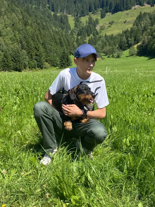 Ein Mann kniet auf einem Feld mit einem Hund. – Jugend und Hund Lager 2022 in Segnas
