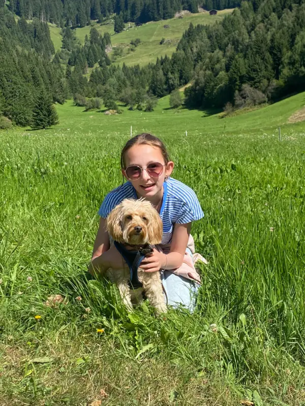 Eine Frau, die auf einem Feld mit einem Hund sitzt. – Jugend und Hund Lager 2022 in Segnas