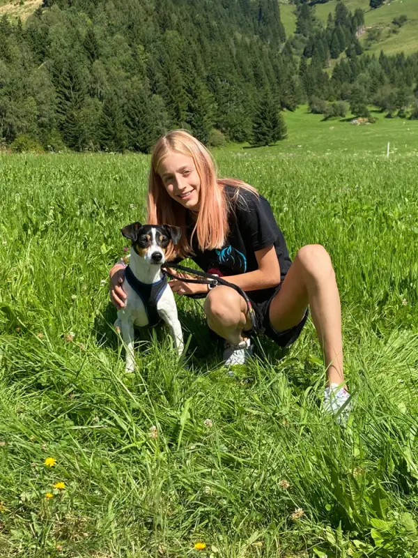 Eine Frau kniet auf einem Feld mit einem Hund. – Jugend und Hund Lager 2022 in Segnas