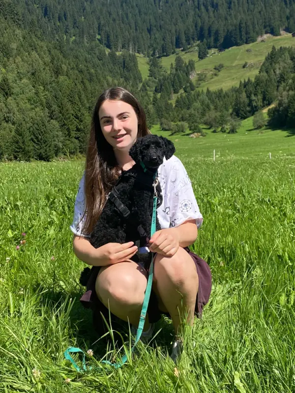 Eine Frau kniet auf einem Feld mit einem Hund. – Jugend und Hund Lager 2022 in Segnas