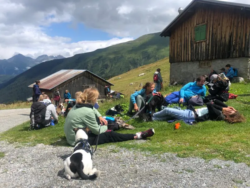Eine Gruppe von Menschen, die vor einem Gebäude auf dem Boden sitzen. – Jugend und Hund Lager 2023 in Segnas