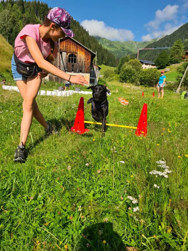 Eine Frau spielt mit ihrem Hund im Gras. – Jugend und Hund Lager 2024 in Segnas