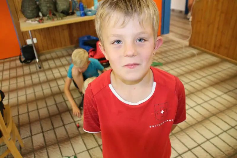 Das Bild zeigt einen Jungen, der vor einem Holztisch steht, auf dem ein Rucksack steht. – Jugend und Hund Lager 2025 in Segnas