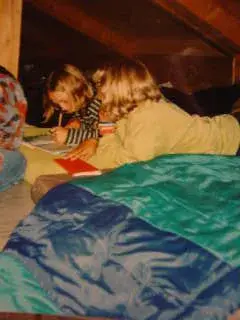 Zwei Kinder, die auf einem Bett in einem Loft liegen, umgeben von einer Decke und einer hölzernen Wand. – Jugend und Hund Lager 2000 in Sörenberg