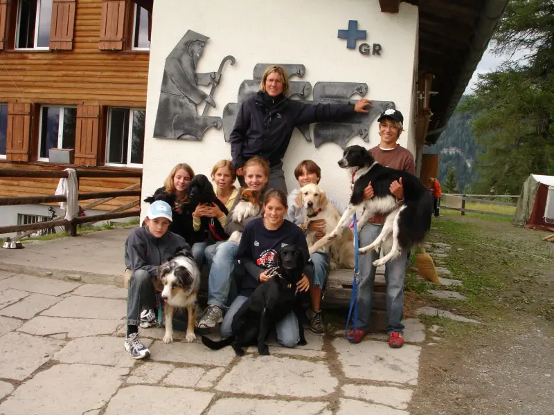Eine Gruppe von Menschen, die auf einer Bank mit Hunden sitzen. – Jugend und Hund Lager 2006 in Trans