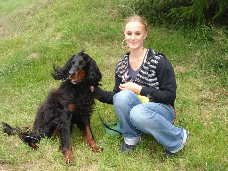 Eine Frau kniet mit einem Hund auf einem Feld nieder. – Jugend und Hund Lager 2007 in Trans