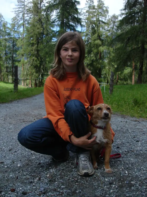 Ein Mädchen sitzt auf einer Schotterstrasse mit einem Hund. – Jugend und Hund Lager 2007 in Trans
