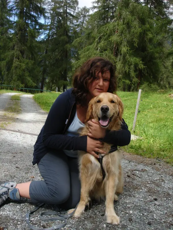 Eine Frau kniet mit einem Hund in ihrem Schoss nieder. – Jugend und Hund Lager 2007 in Trans