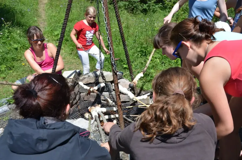 Eine Gruppe von Menschen, die um ein Feuer versammelt sind, mit einigen Brillen. – Jugend und Hund Lager 2012 in Vignogn