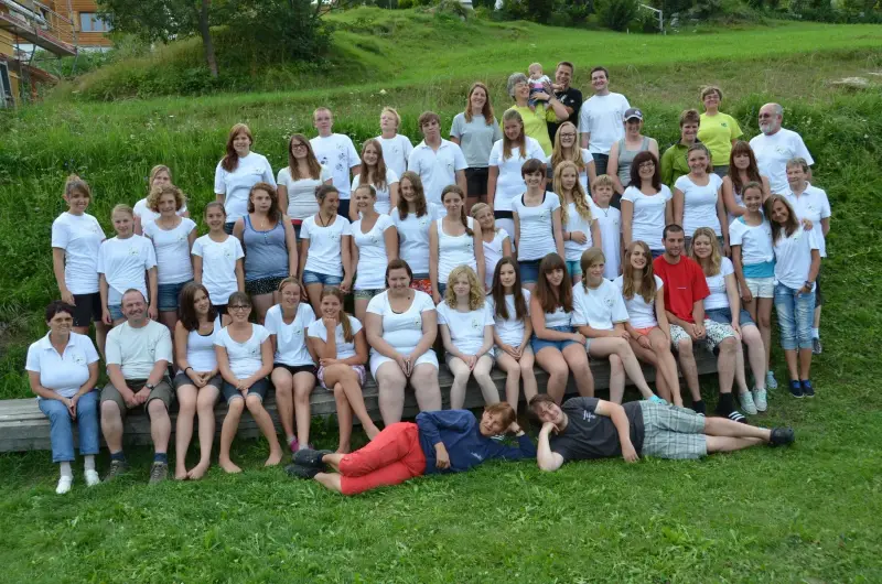Eine Gruppe von Menschen, die für ein Foto auf einem Grasfeld posieren. – Jugend und Hund Lager 2012 in Vignogn