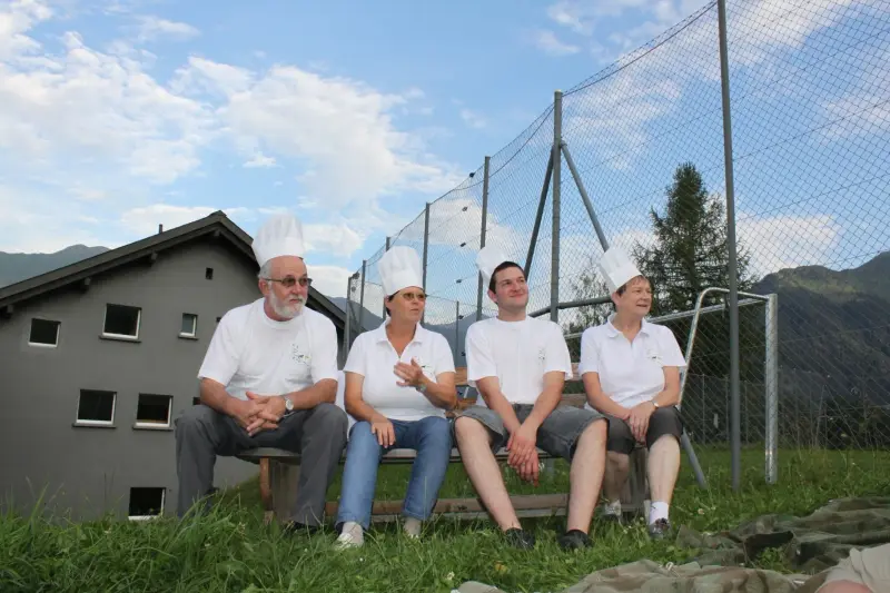 Eine Gruppe von Menschen, die auf einem grasbedeckten Feld sitzen. – Jugend und Hund Lager 2012 in Vignogn