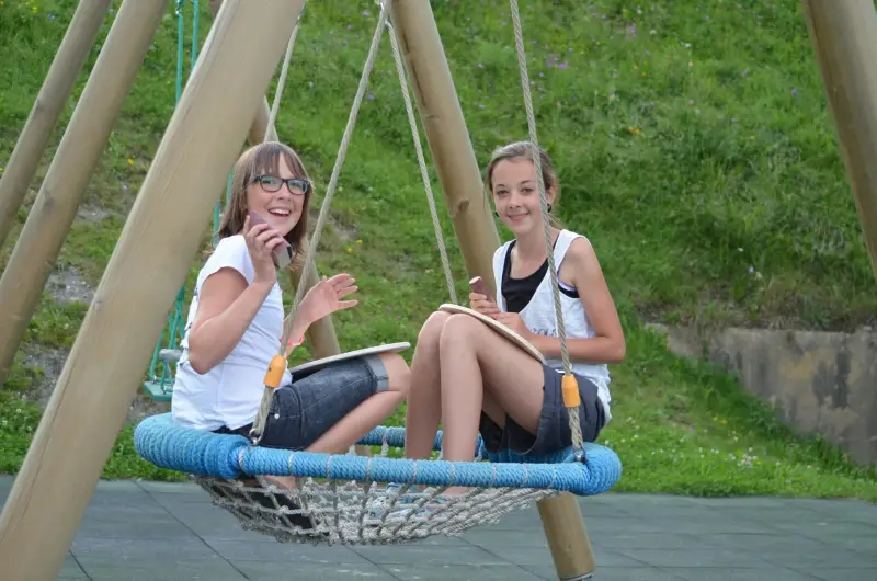 Zwei junge Mädchen, die in einer Schaukel in einem Park sitzen. – Jugend und Hund Lager 2012 in Vignogn