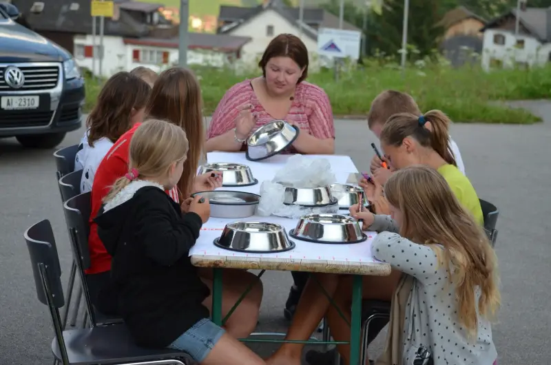 Eine Gruppe von Kindern, die um einen Tisch mit Schalen von Lebensmitteln sitzen. – Jugend und Hund Lager 2012 in Vignogn